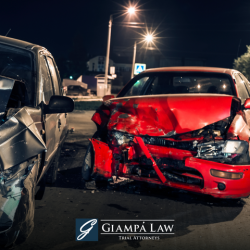 A red car with heavy damage to the front end in the road after a nighttime accident in Mount Vernon