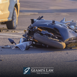 After a Mount Vernon motorcycle accident, a visibly damaged motorcycle lies in the road next to a yellow car